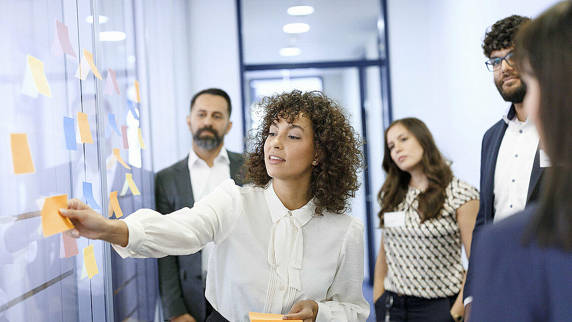 A group of Leadec employees in front of a wall with sticky notes at a workshop in the office.